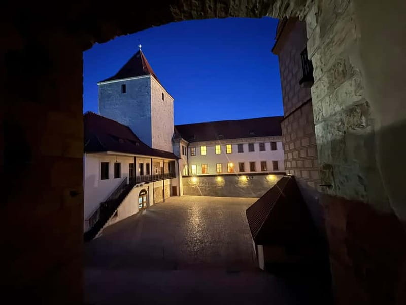 Prague: Night Walk through Prague Castle with City Views - Crossing into the castle grounds: moat, fortifications, and first lights